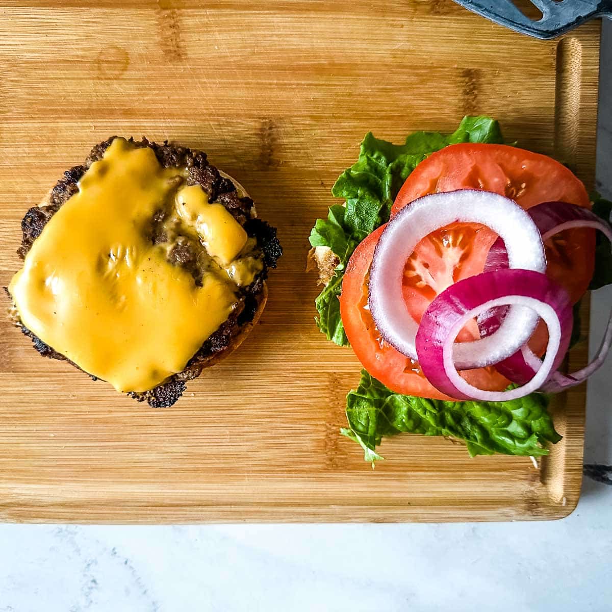 Building a turkey smash burger on a wooden cutting board.