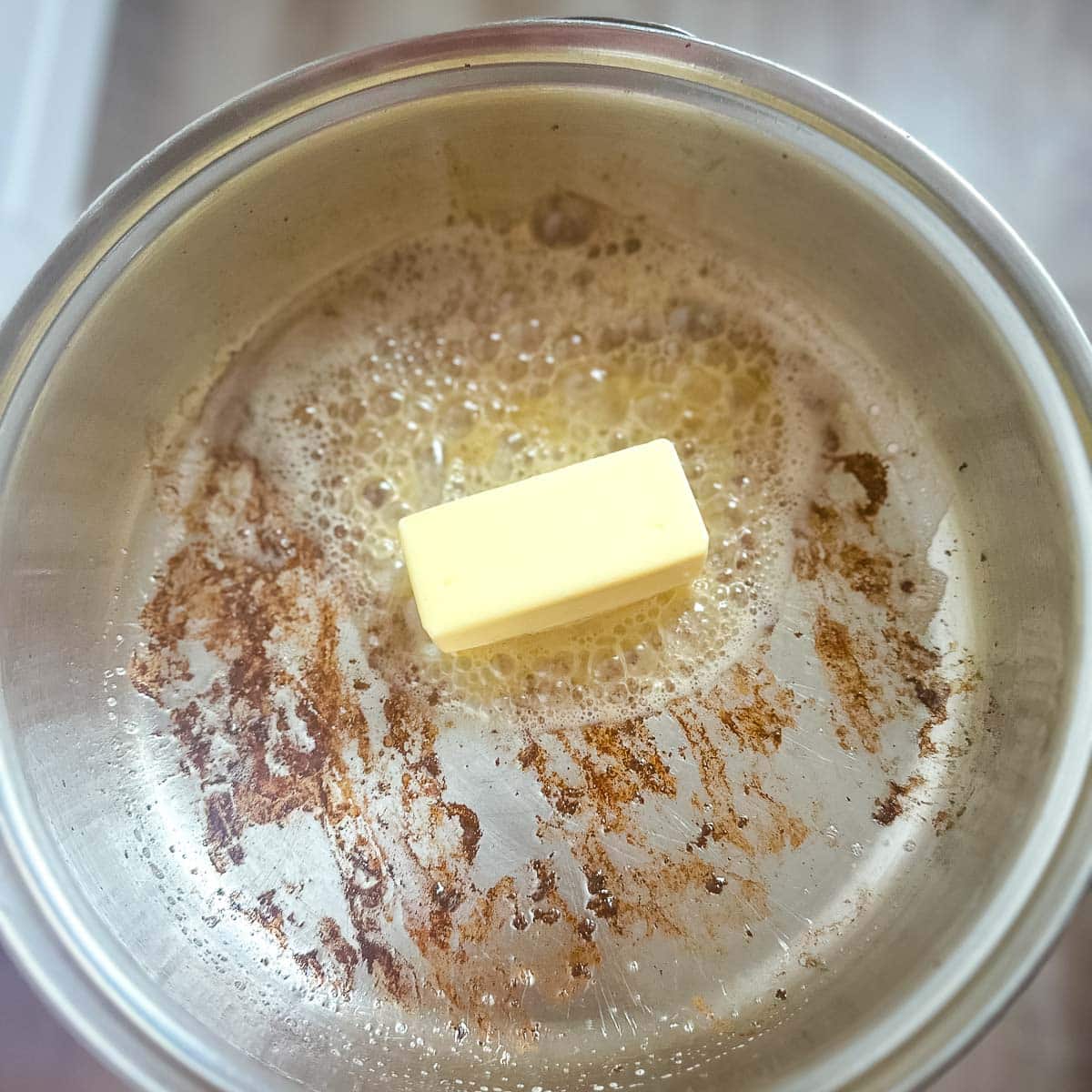 Butter is melted in a pan with bacon fat.