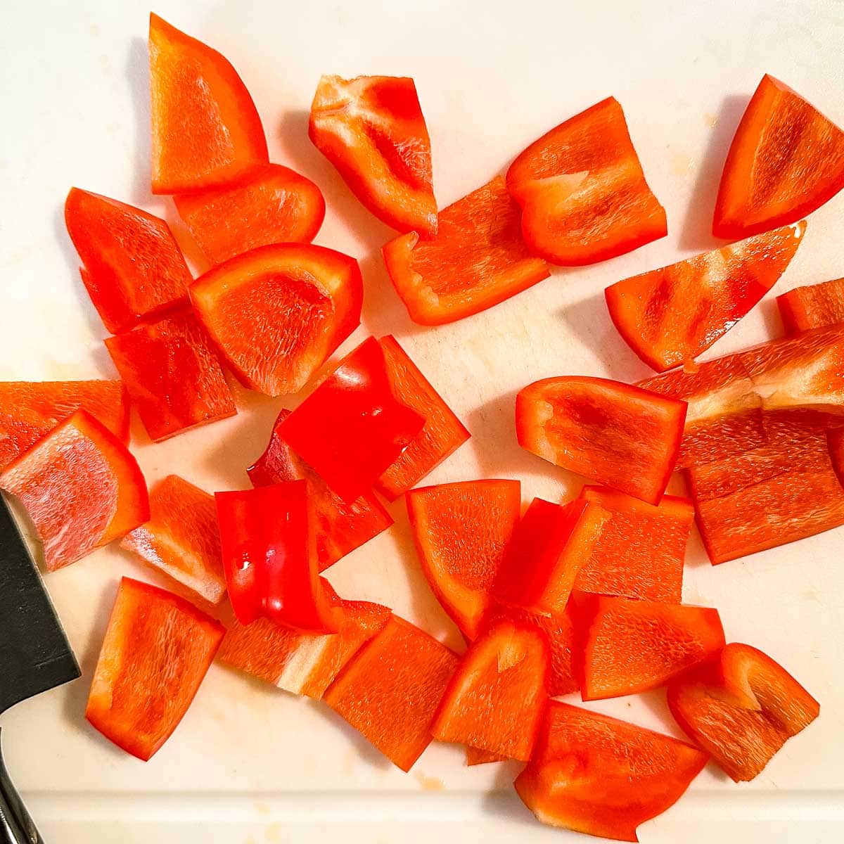 Chopped red bell pepper on a white cutting board.