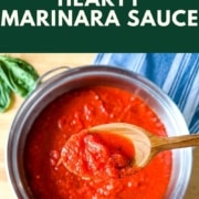 A spoonful of marinara sauce over a pot of marinara sauce is shown with the words Hearty Marinara Sauce and the URL www.twocloveskitchen.com.