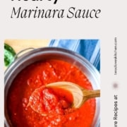 A spoonful of marinara sauce over a pot of marinara sauce is shown with the words Hearty Marinara Sauce and the URL www.twocloveskitchen.com.