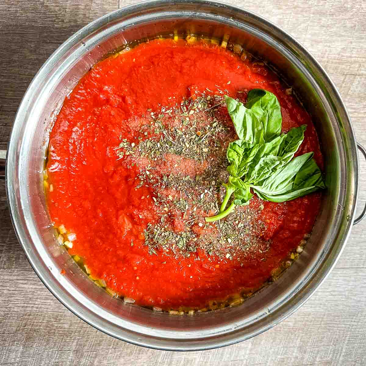 Tomatoes, Italian herbs, salt, pepper, and fresh basil are added to the pot.