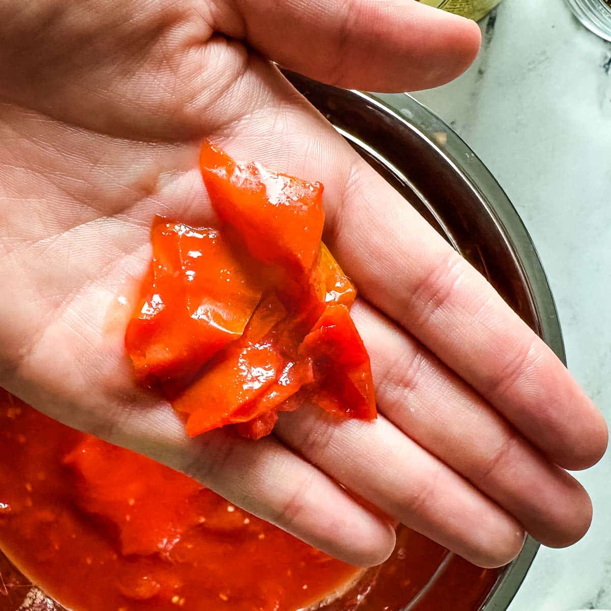 The peel from a tomato is shown in the palm of a person's hand.
