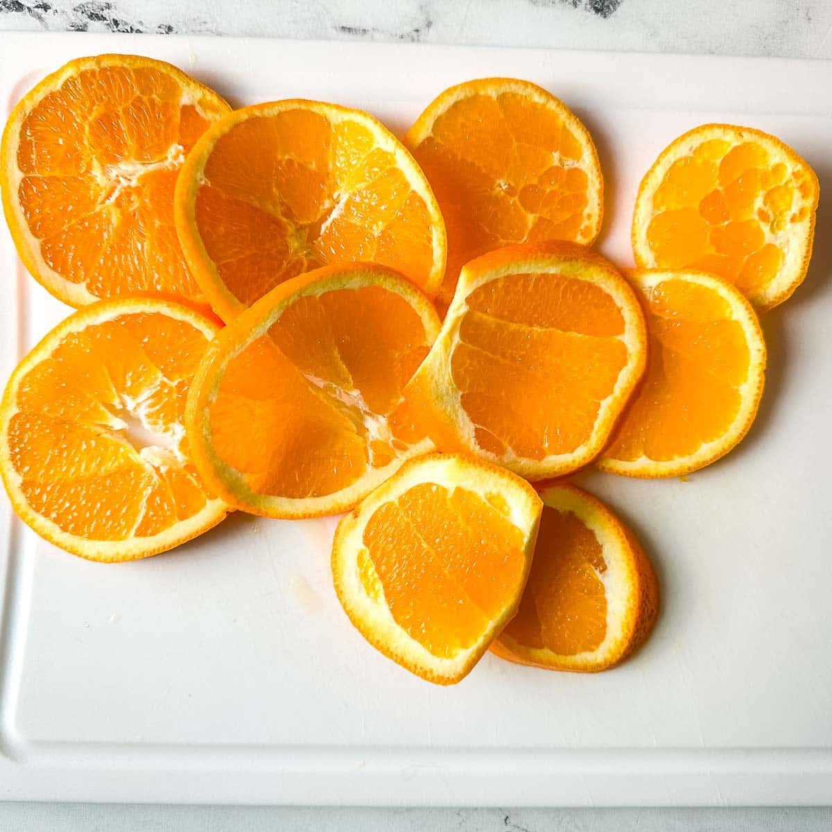 Sliced oranges on a white cutting board.