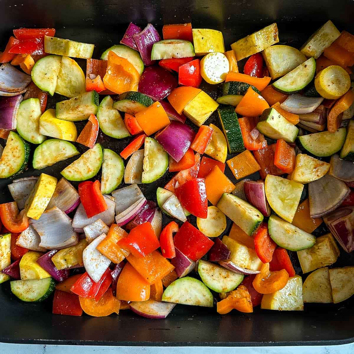 Cut and seasoned vegetables are shown in a roasting pan.