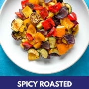 Roasted vegetables on a white dish with the words Spicy Roasted Vegetables and the URL www.twocloveskitchen.com.