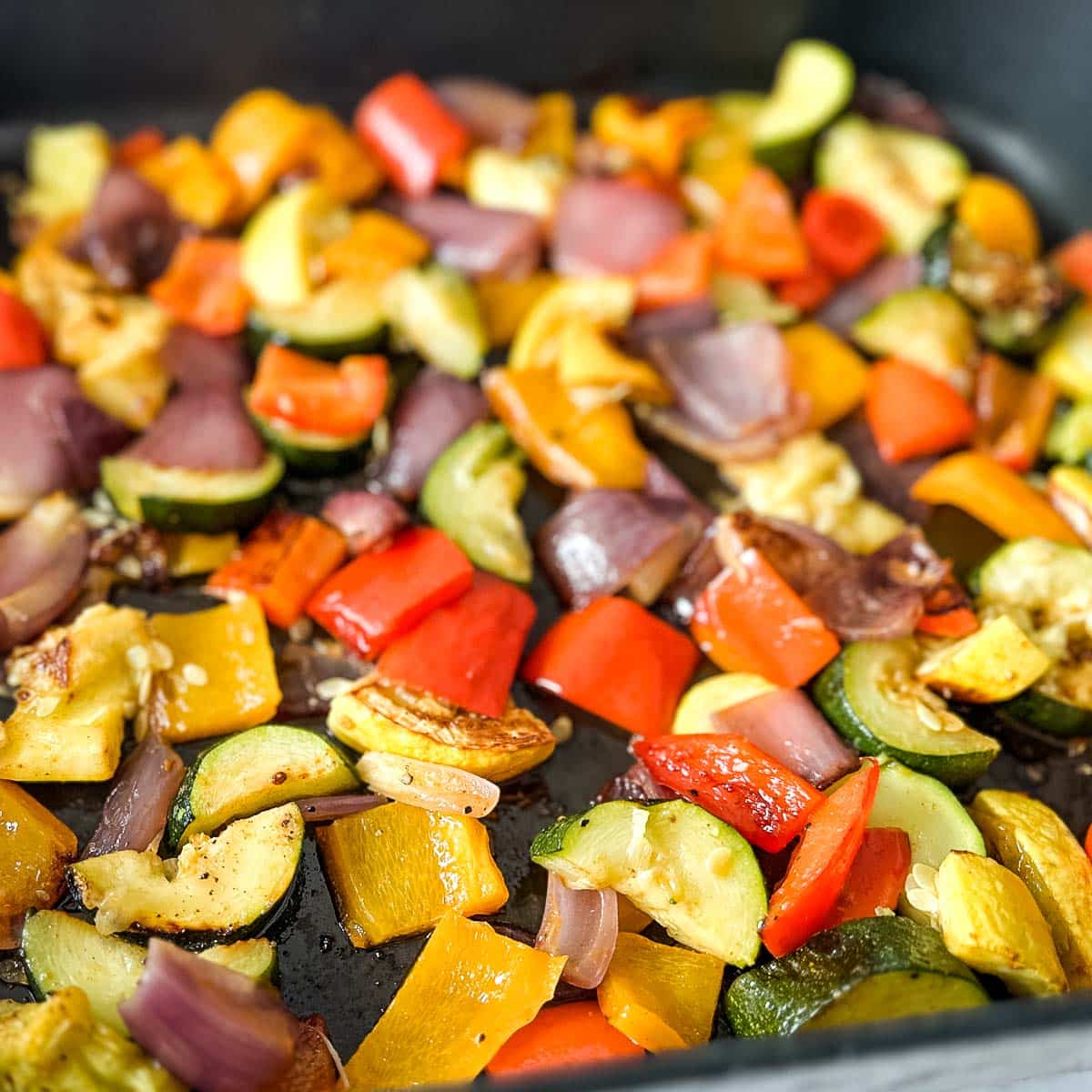 Closeup of spicy roasted vegetables in a roasting pan.