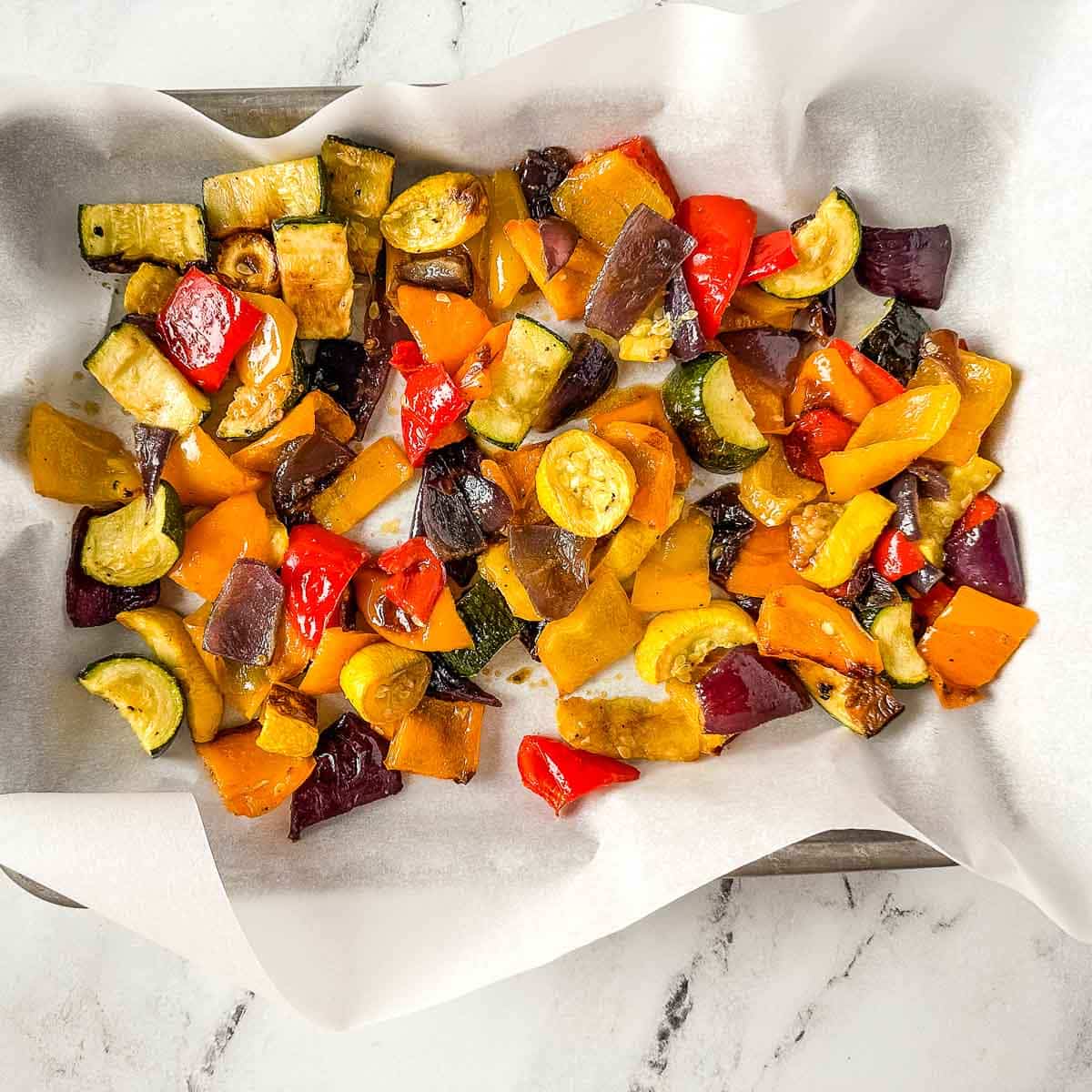 Roasted vegetables on a lined sheet tray.
