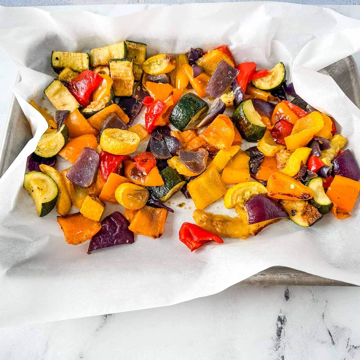 Frozen roasted vegetables on a lined sheet tray.