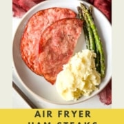 ham steak with asparagus and mashed potatoes with the words air fryer ham steaks and the URL two cloves kitchen dot com.