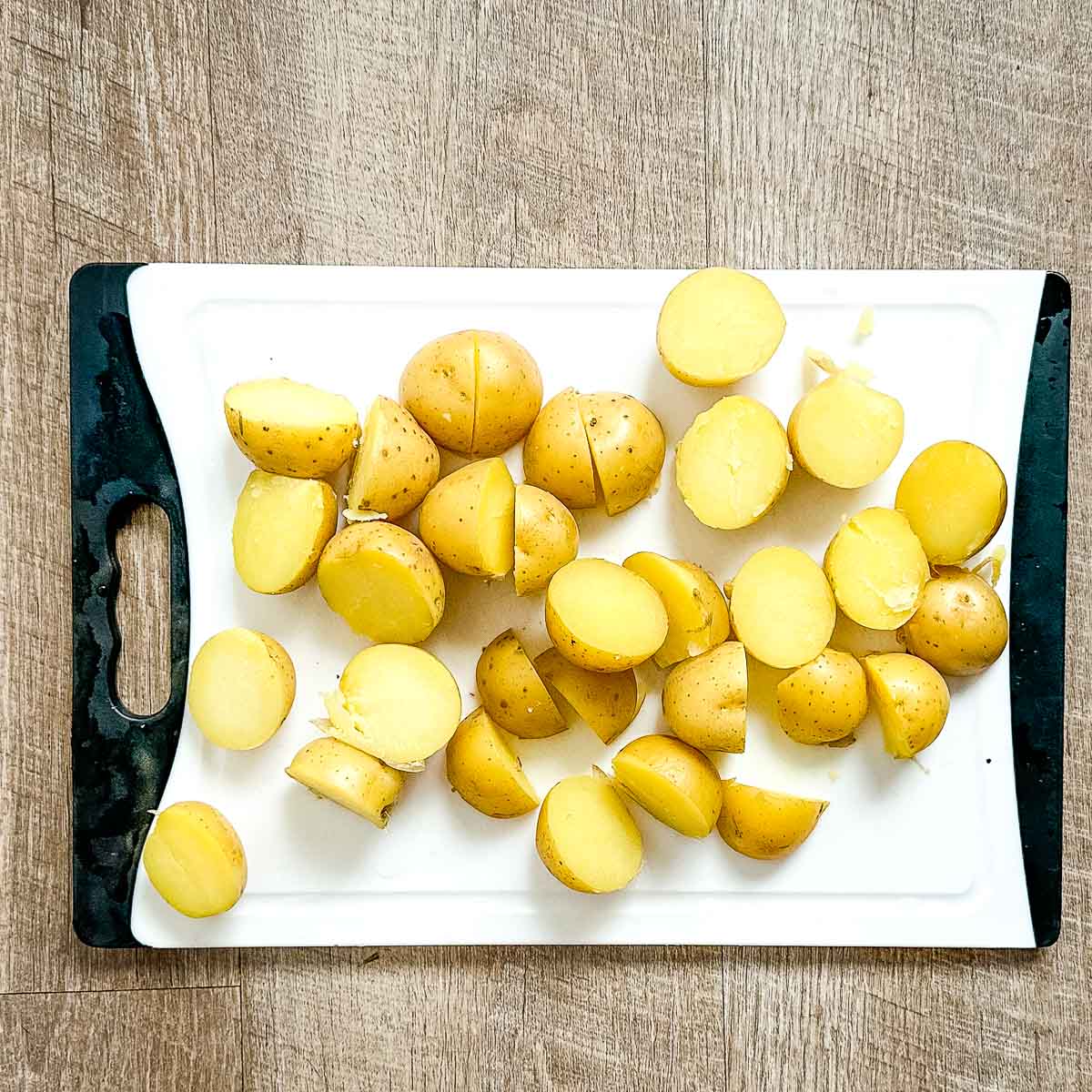 cooked, halved yukon gold potatoes on a white cutting board.