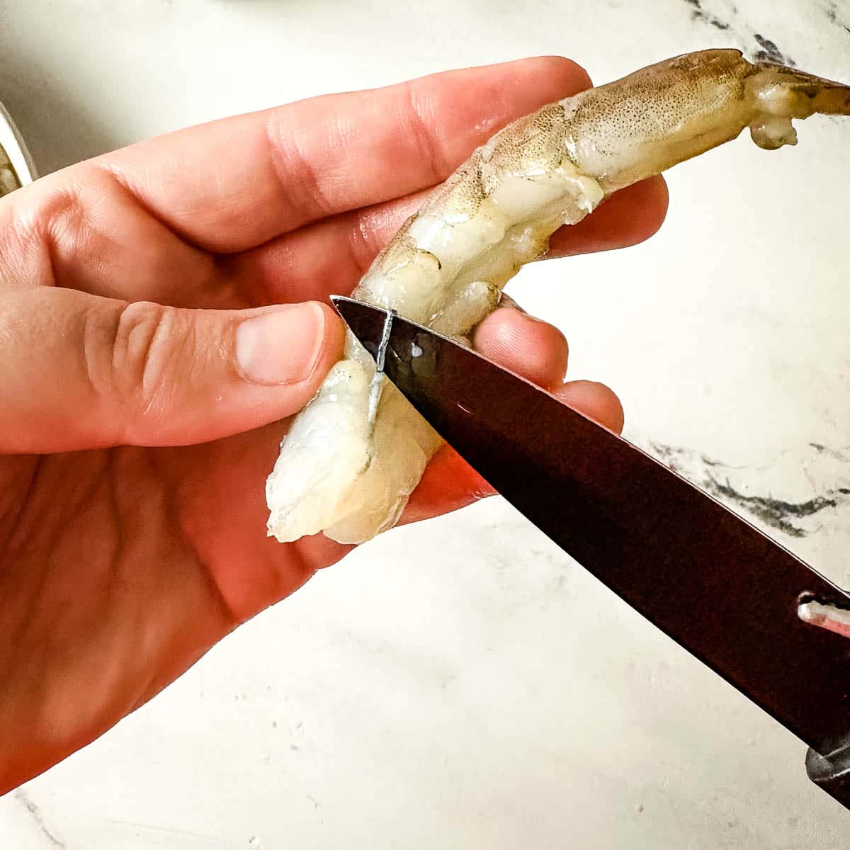 deveining shrimp with a black paring knife.