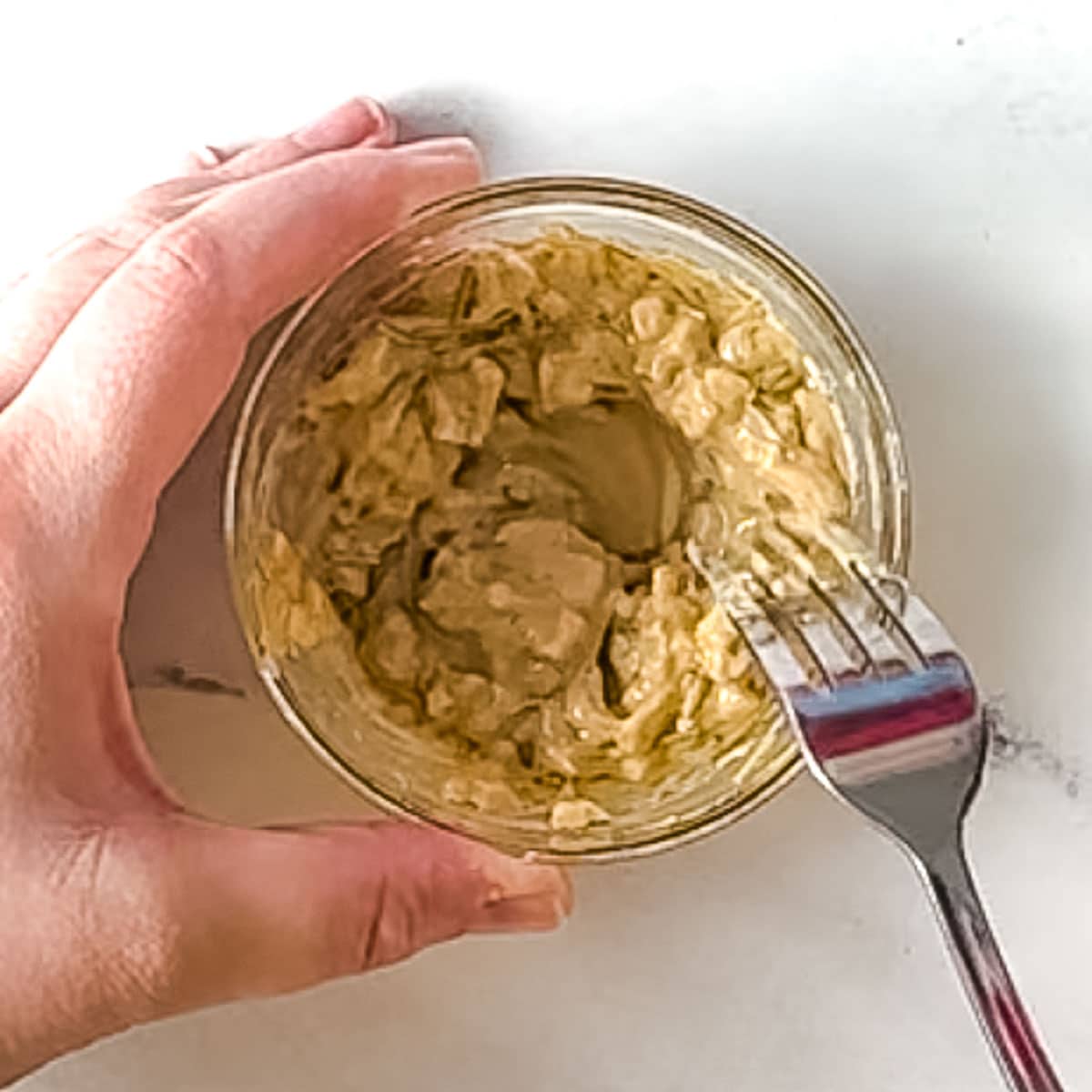 dijon mustard, chopped garlic, olive oil, and rosemary are mixed in a glass bowl.