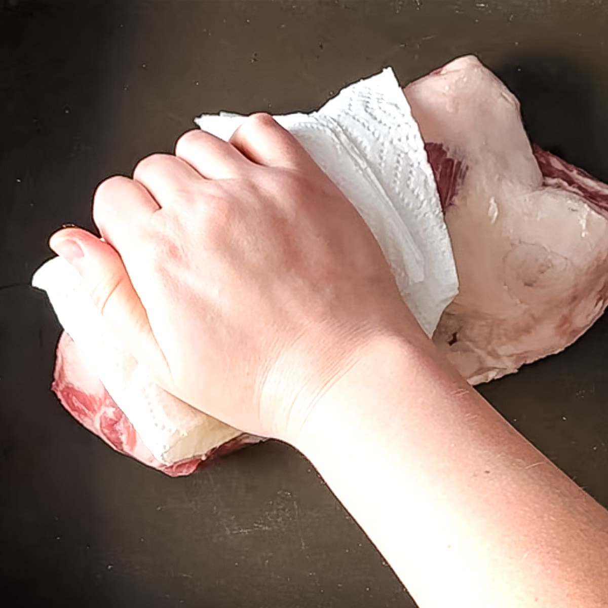 lamb breast is patted dry with a paper towel.