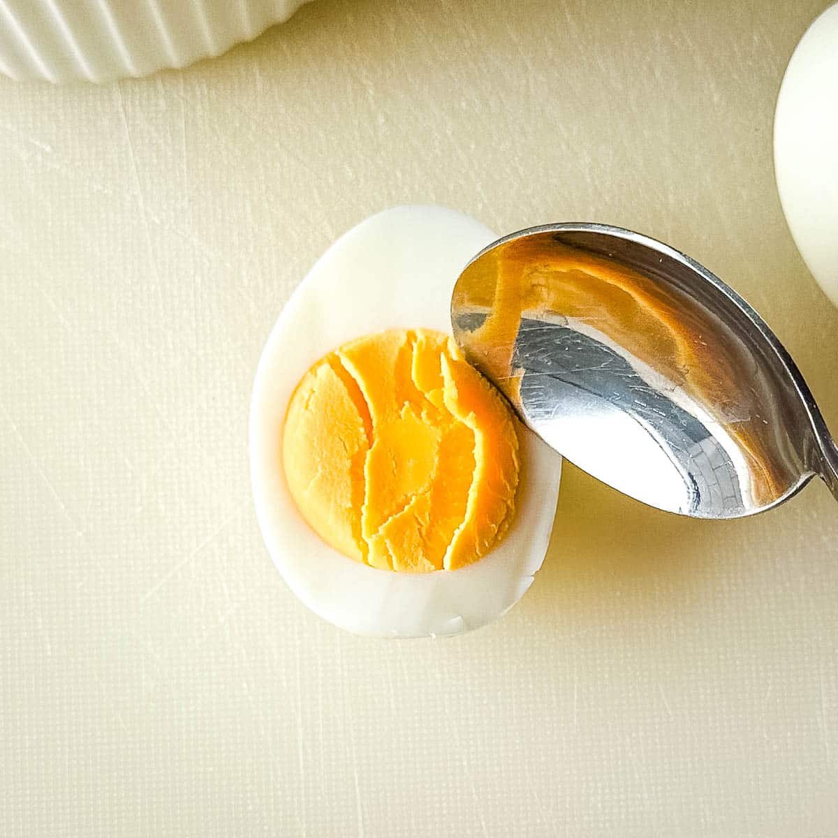 Removing yolk from hard-boiled egg with spooon.