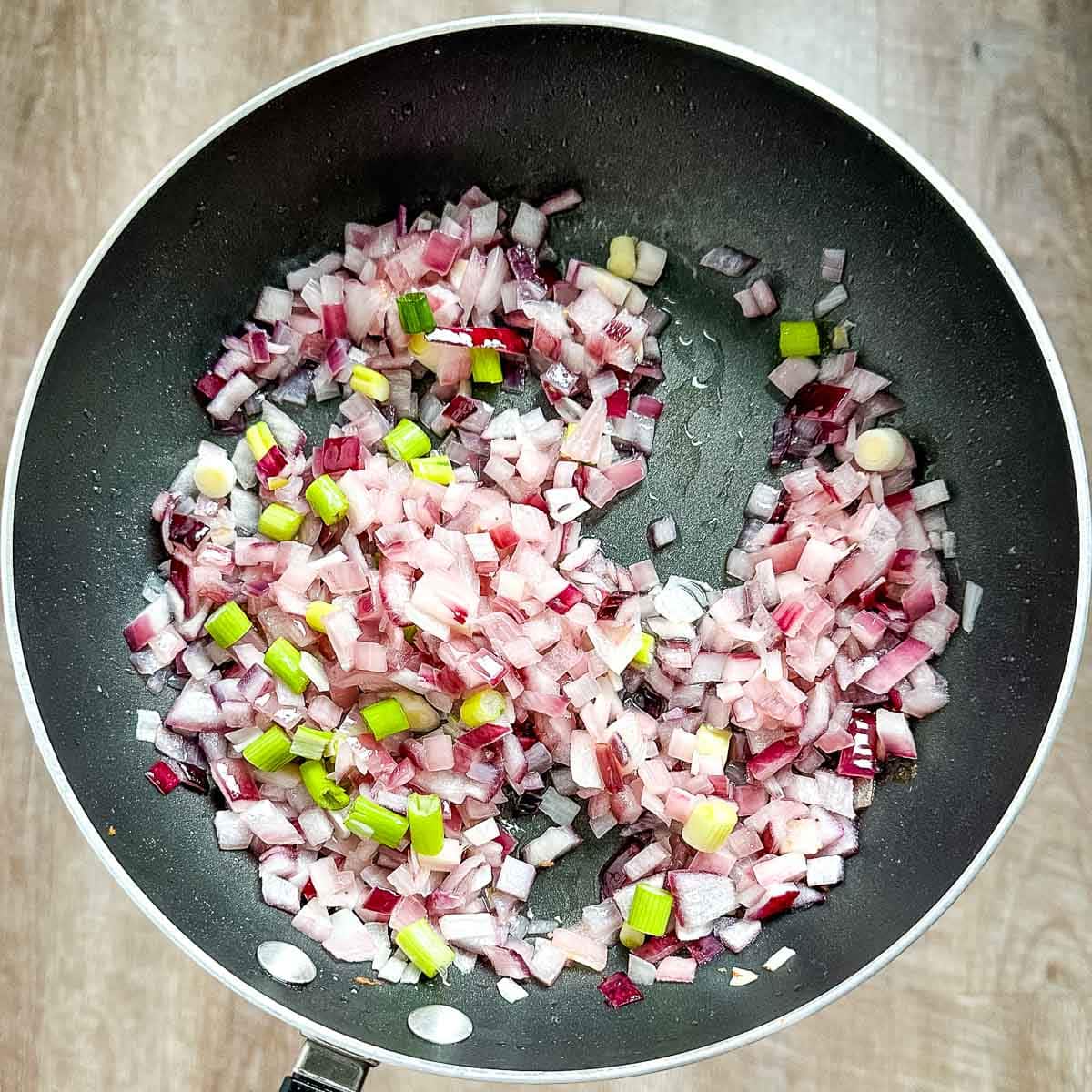 scallions added to a pan with cooked onions and bacon fat.
