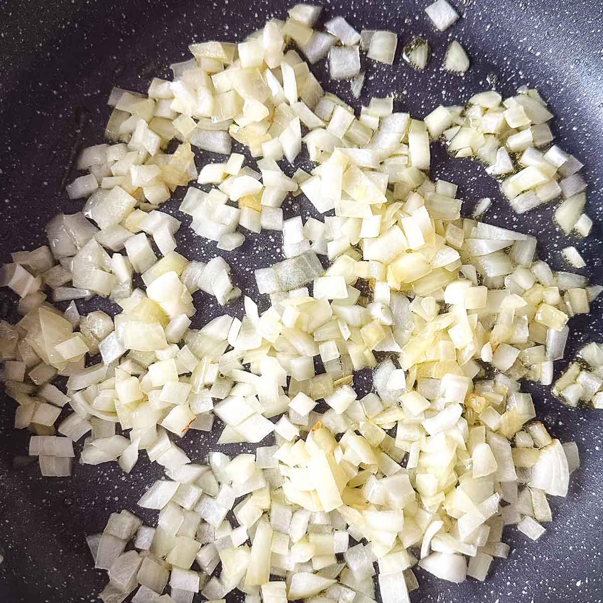 chopped onion sweating in a frying pan.