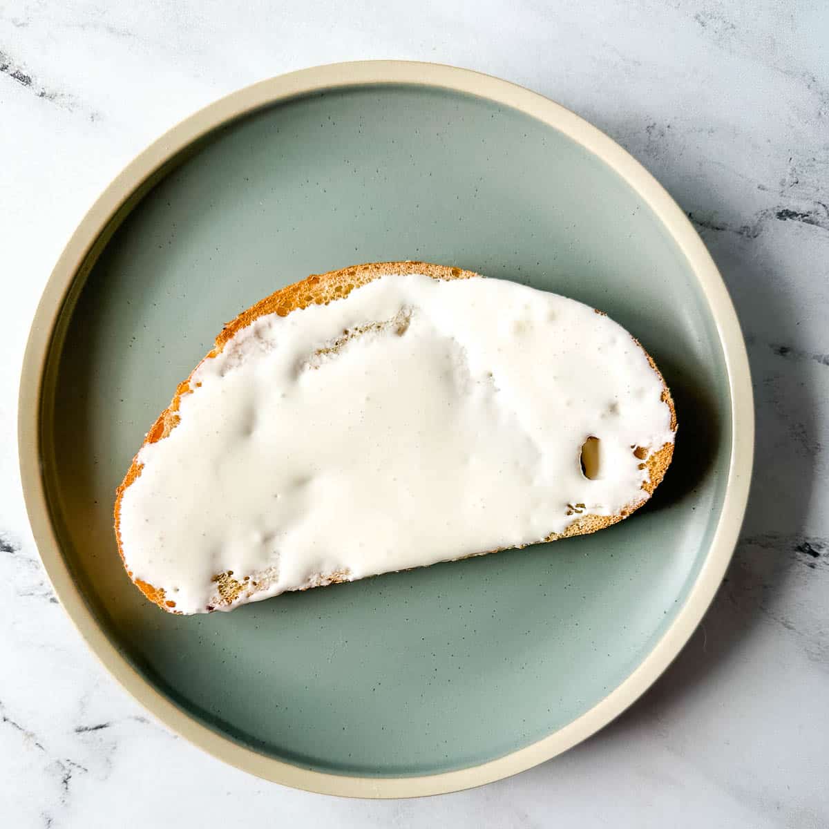 Toast spread with cream cheese on a blue plate.