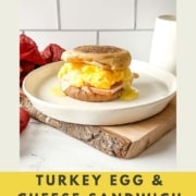Side view of a turkey egg and cheese sandwich on a white plate with the words Turkey Egg and Cheese Sandwich and the URL for two cloves kitchen dot com.