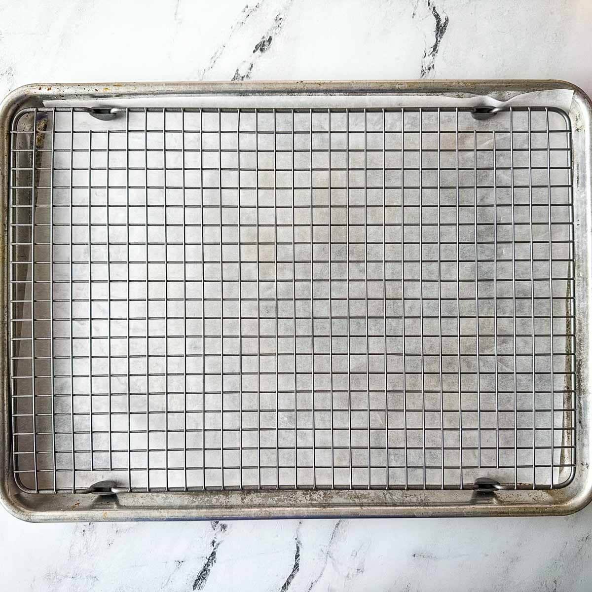 A baking sheet lined with parchment paper with a wire baking rack on top.