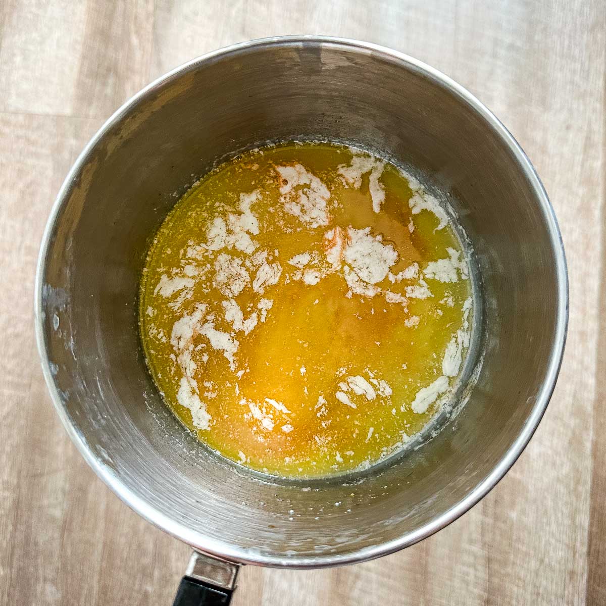 Hot sauce is added to melted butter in a saucepot.