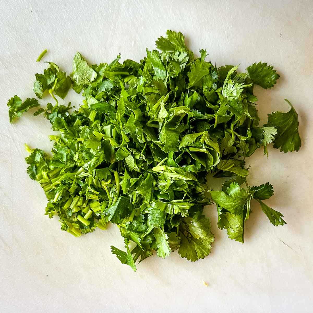 Chopped cilantro on a white cutting board.