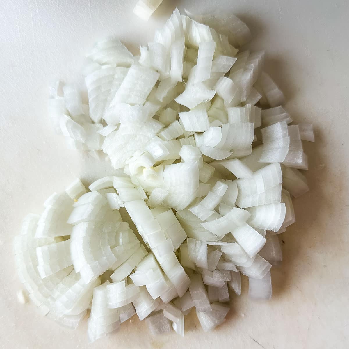 Chopped onion on a white cutting board.
