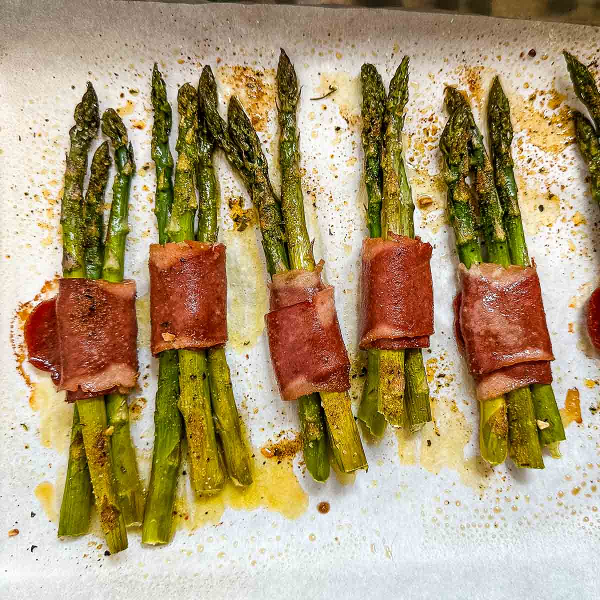 cooked turkey bacon wrapped asparagus on a sheet tray.