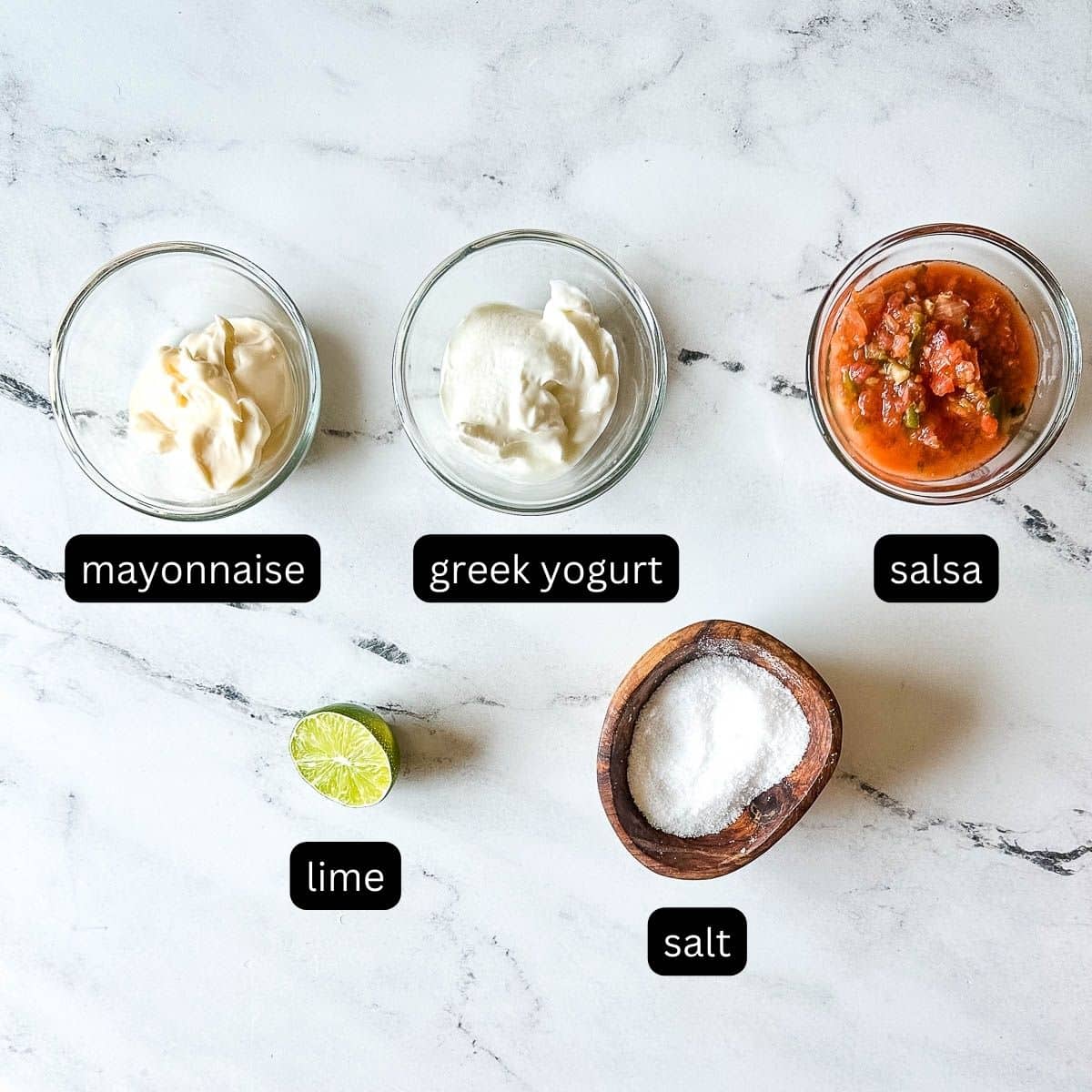 Labeled ingredients for creamy salsa dressing on a white marble counter.