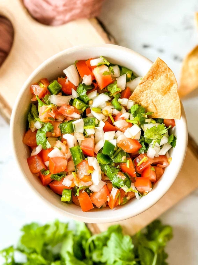 Garden fresh salsa in a white bowl on a vintage wooden cutting board.