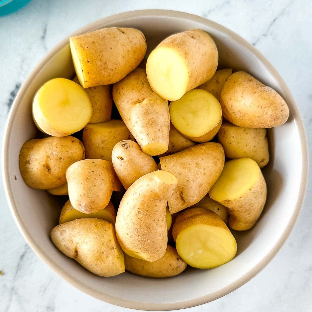 Halved fingerling potatoes in a white bowl.