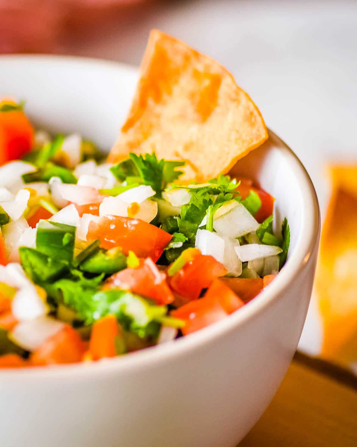 A closeup side shot of garden fresh salsa in a white bowl.
