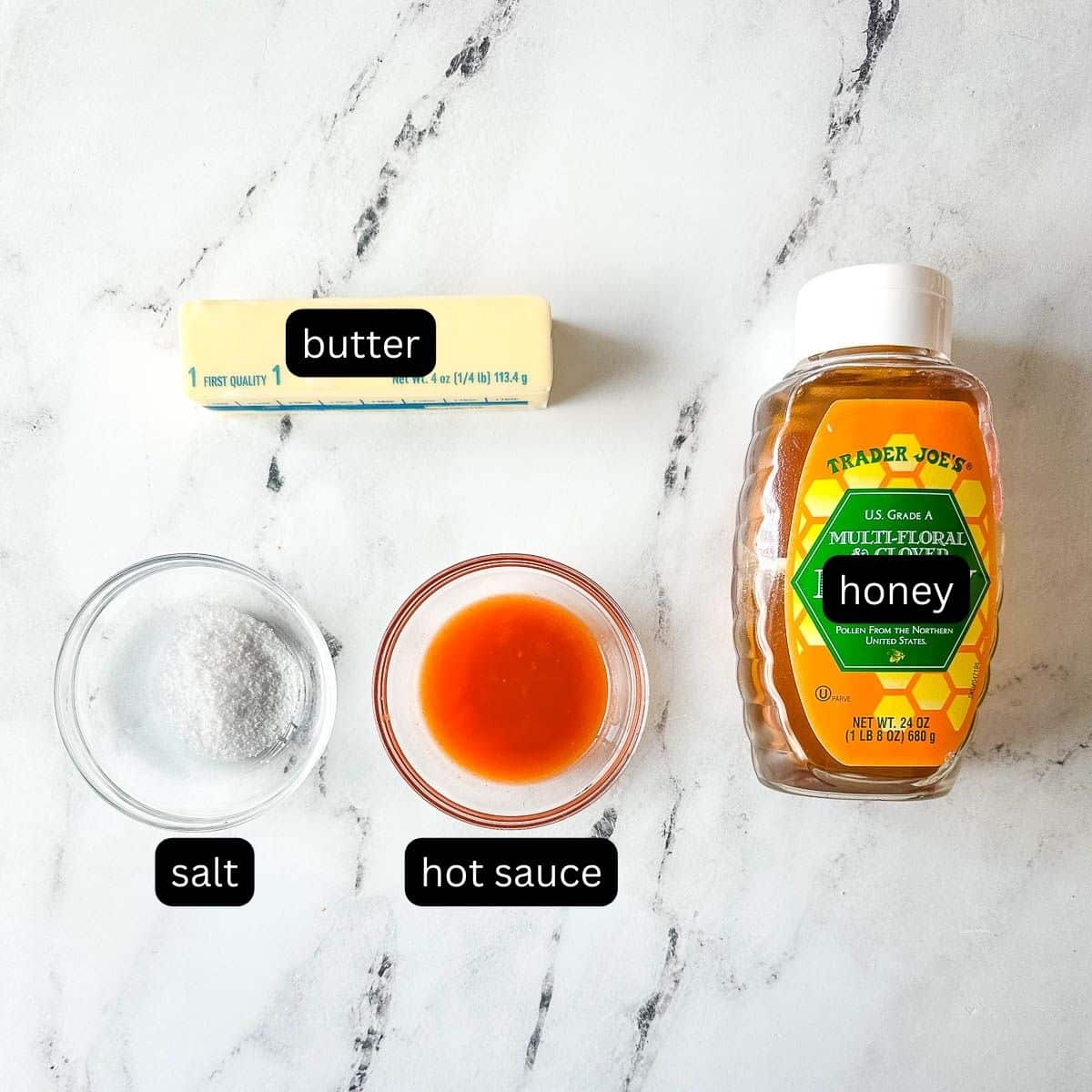 Labeled ingredients for hot honey sauce on a white marble counter.