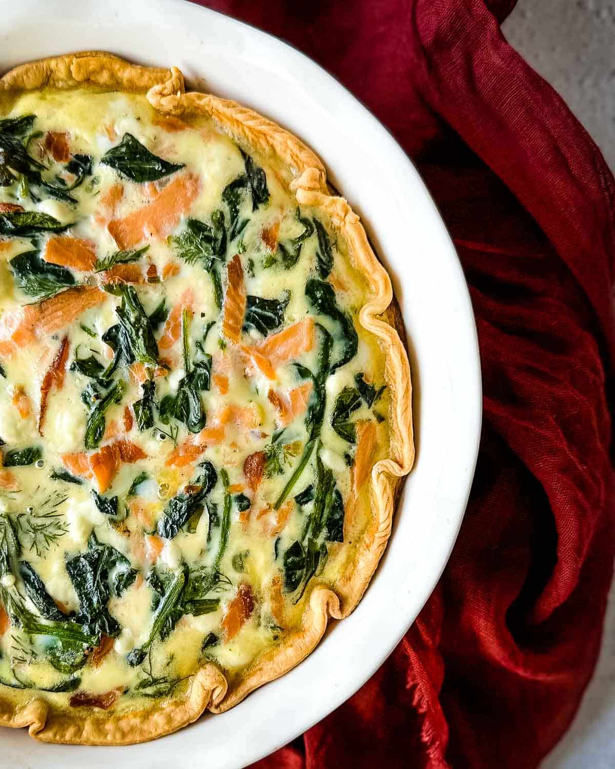 Overhead shot of smoked salmon spinach quiche in a white pie dish.