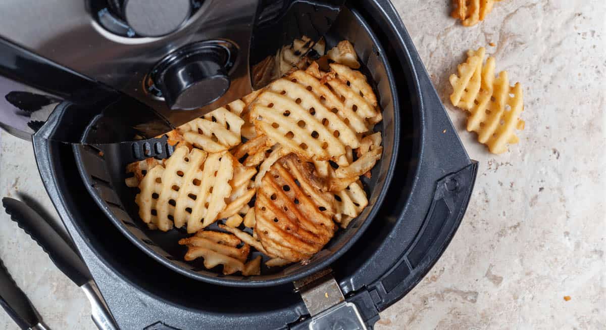 Waffle cut fries are shown in an air fryer basket.