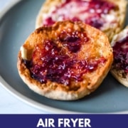 Toasted english muffins with butter and jam sit on a blue plate with the words air fryer english muffins and the web address two cloves kitchen dot com.