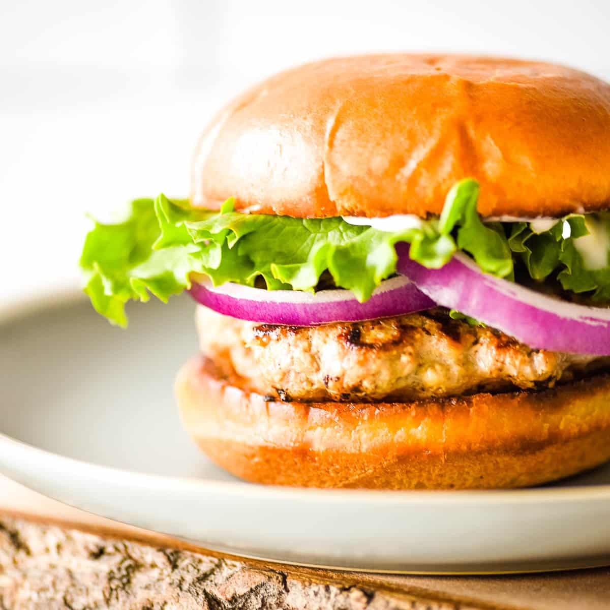 A closeup side view is shown of an air fryer turkey burger on a light blue plate.