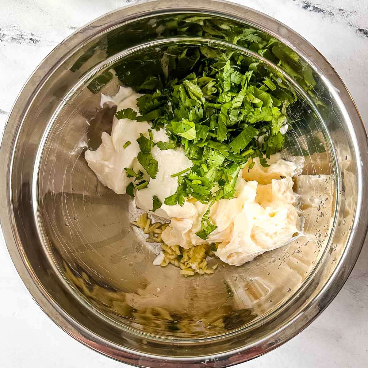 The ingredients for cilantro lime crema in a silver bowl.