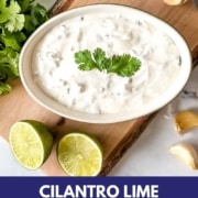 Crema in a dish surrounded by limes, garlic and cilantro with the words Cilantro Lime Crema and the web address two cloves kitchen dot com.