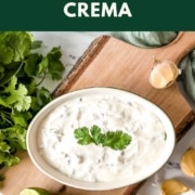Crema in a dish surrounded by limes, garlic and cilantro with the words Cilantro Lime Crema and the web address two cloves kitchen dot com.