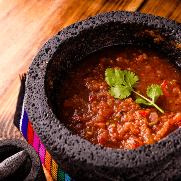 Salsa roja in a mortar on a wooden table.