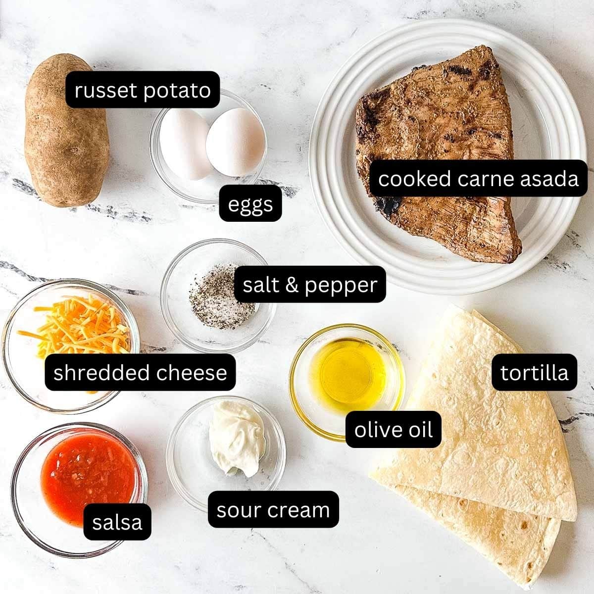 The labeled ingredients for carne asada breakfast burritos sit on a white marble counter.