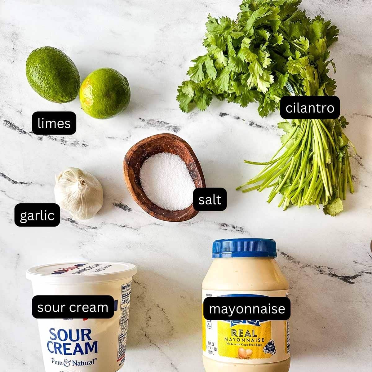 The labeled ingredients for cilantro lime crema sit on a white marble counter.