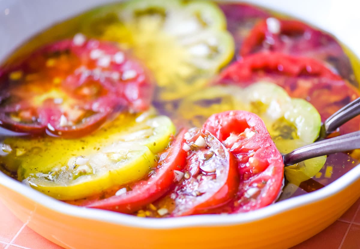Closeup of marinated heirloom tomatoes in a yellow and white pie dish.