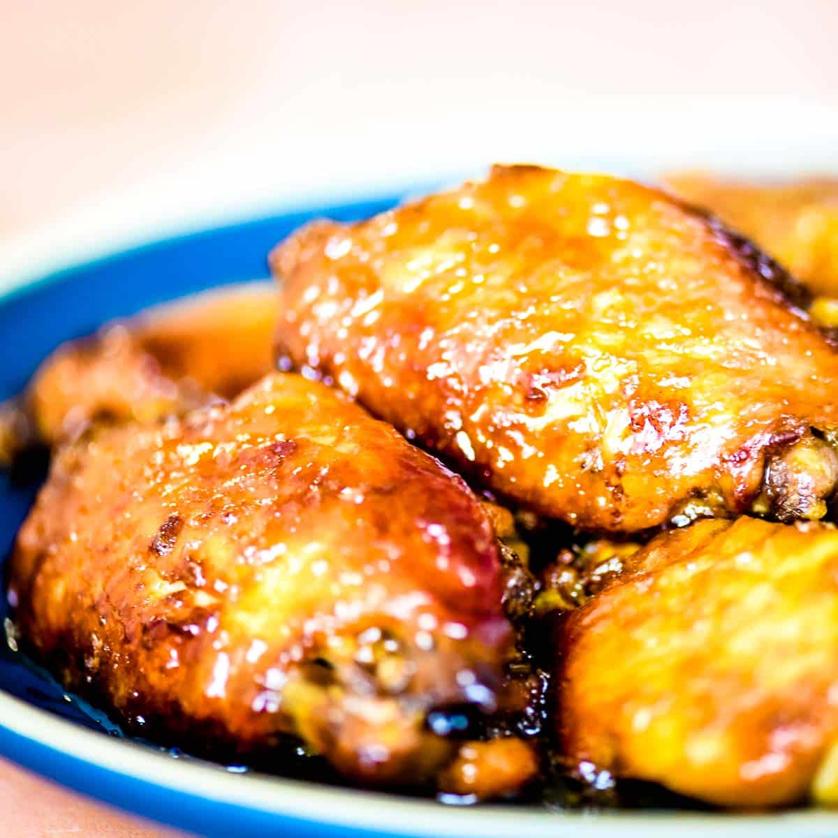 A closeup side view shot of soy garlic wings on a blue plate.