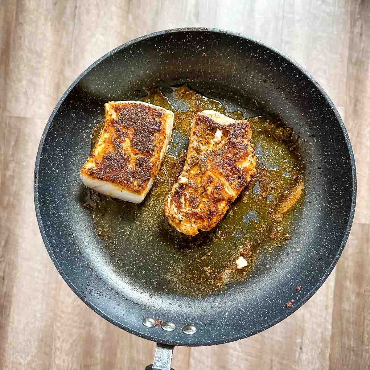 Blackened cod in a frying pan.
