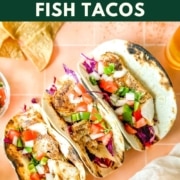 Fish tacos on a peach background with the words blackened fish tacos and the web address two cloves kitchen dot com.