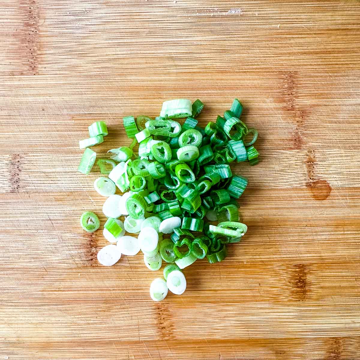 Chopped scallions on a wooden cutting board.