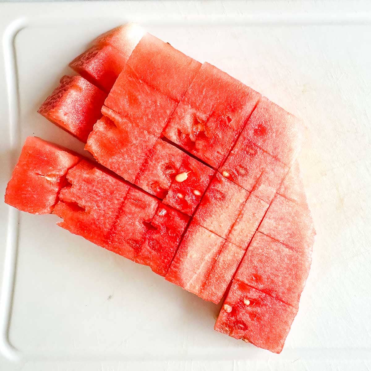 Cubed watermelon on a cutting board.