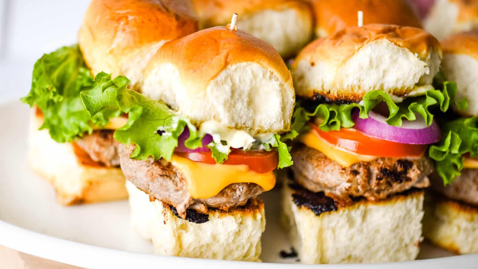 Closeup shot of turkey burger sliders on a white tray.